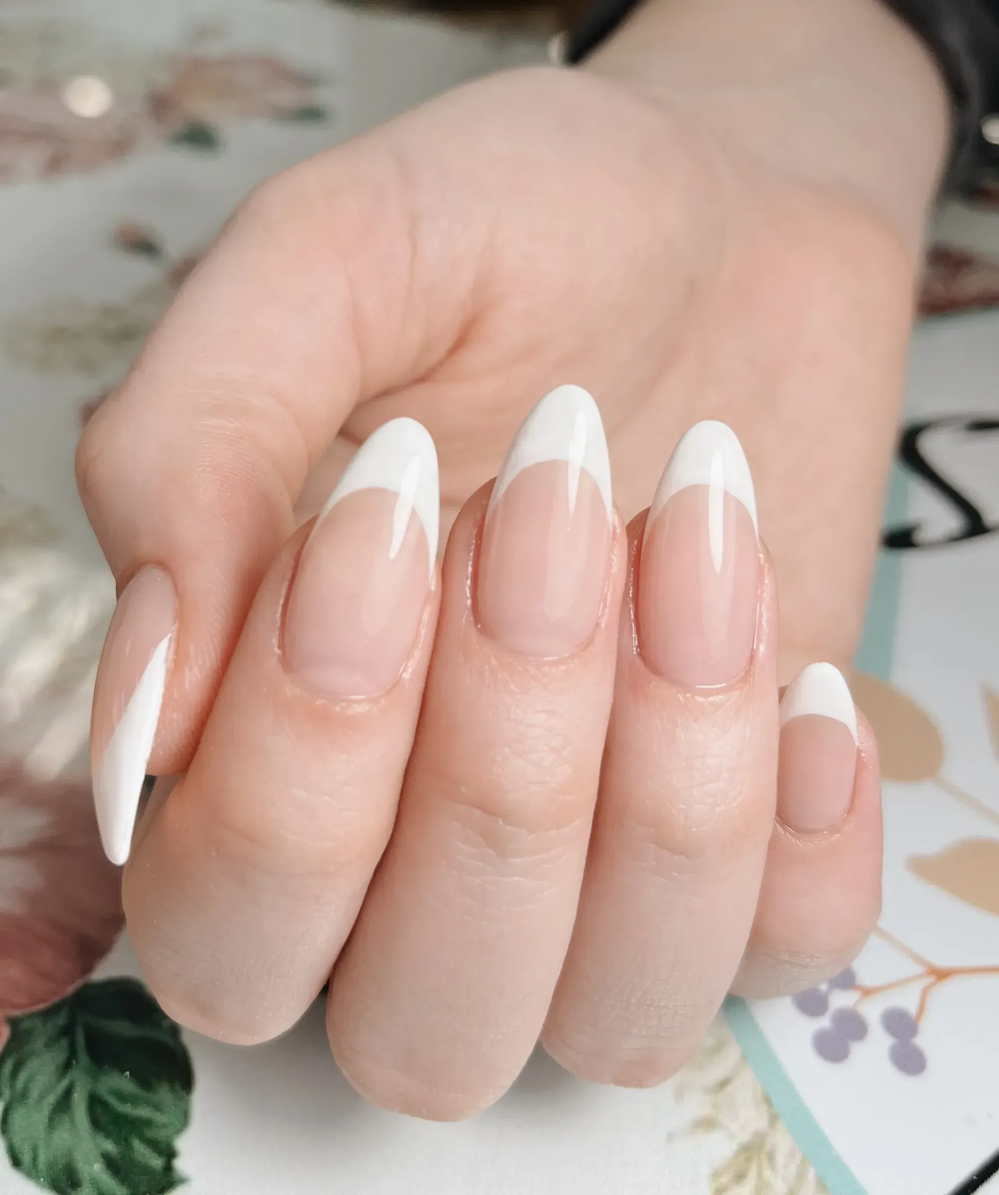 Primer plano de manos con extensiones Gel-X en forma almendrada y francesa blanca, trabajo de Cecilia Alvarez